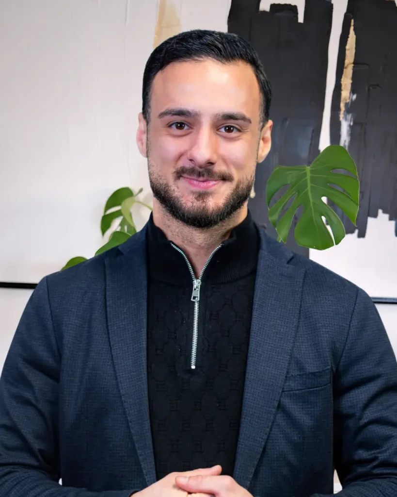 Can Cevir steht lächelnd im Büro von BetonGold Immobilien und vermittelt einen Eindruck von Professionalität und Engagement in der Immobilienbranche