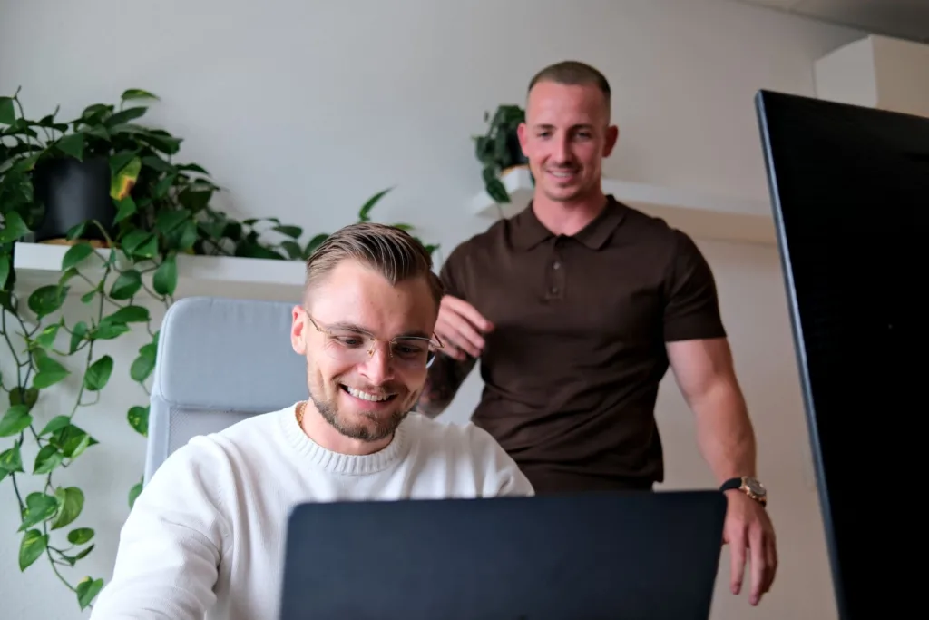 Mike Grammel und Mike Baudendistel beraten sich in einem modernen Büro von BetonGold Immobilien, während sie sich über eine Kapitalanlage-Immobilie austauschen