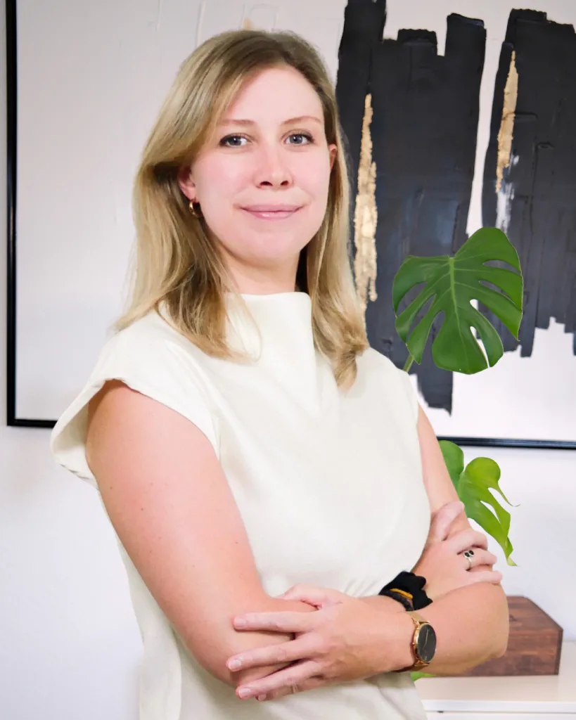 Sabrina präsentiert sich in einem modernen Büro mit einer entspannenden Atmosphäre und vermittelt Kompetenz und Professionalität im Bereich Kapitalanlage-Immobilien