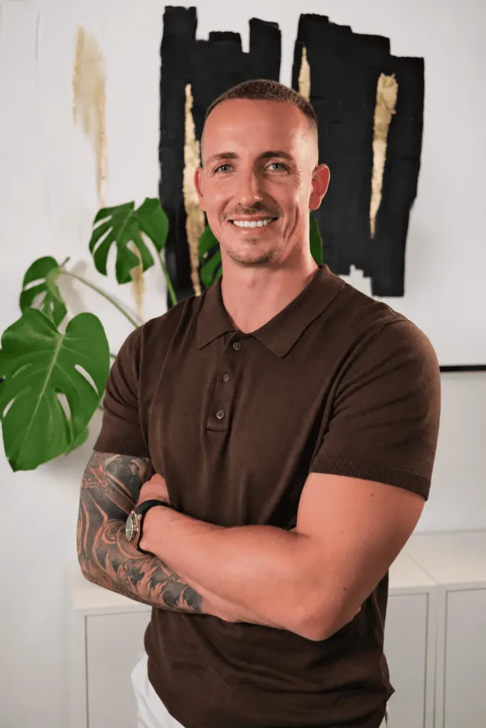 Mike Baudendistel präsentiert sich in einem freundlichen Büroambiente, das durch moderne Kunst und Pflanzen aufgelockert wird, und strahlt Professionalität sowie Vertrauenswürdigkeit aus