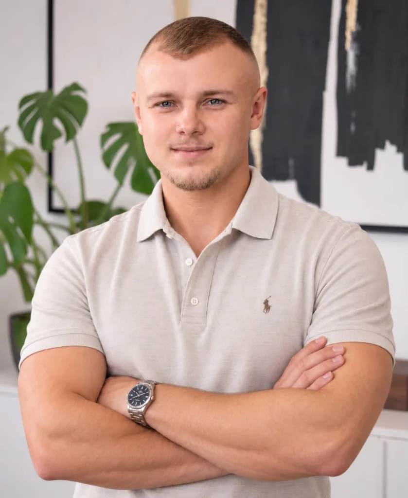 Rafael Lamm steht mit verschränkten Armen in einem modernen Büro, das den Fokus auf seine professionelle Ausstrahlung legt
